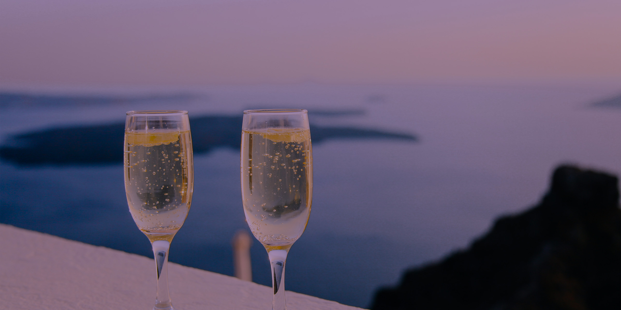 Two wine glasses filled overlooking the ocean